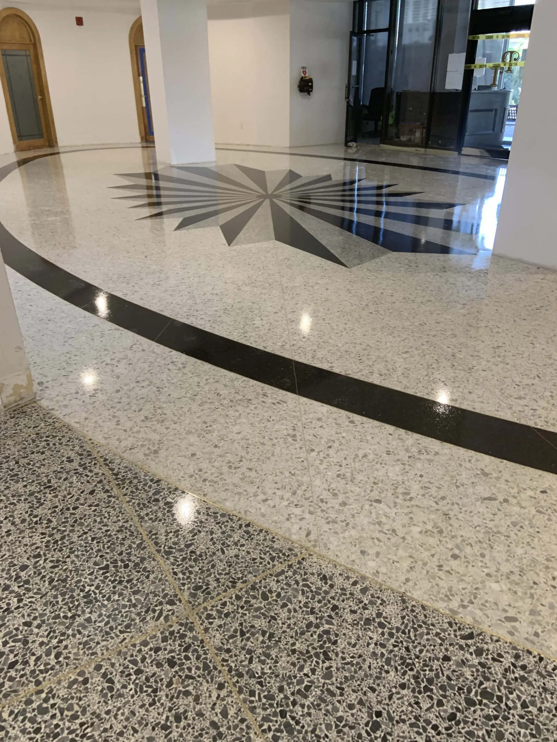 Decorative epoxy terrazzo floor with large black geometric star pattern and curved lines