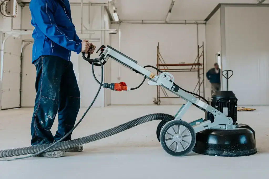 Worker operating a diamond floor polishing machine in a commercial space