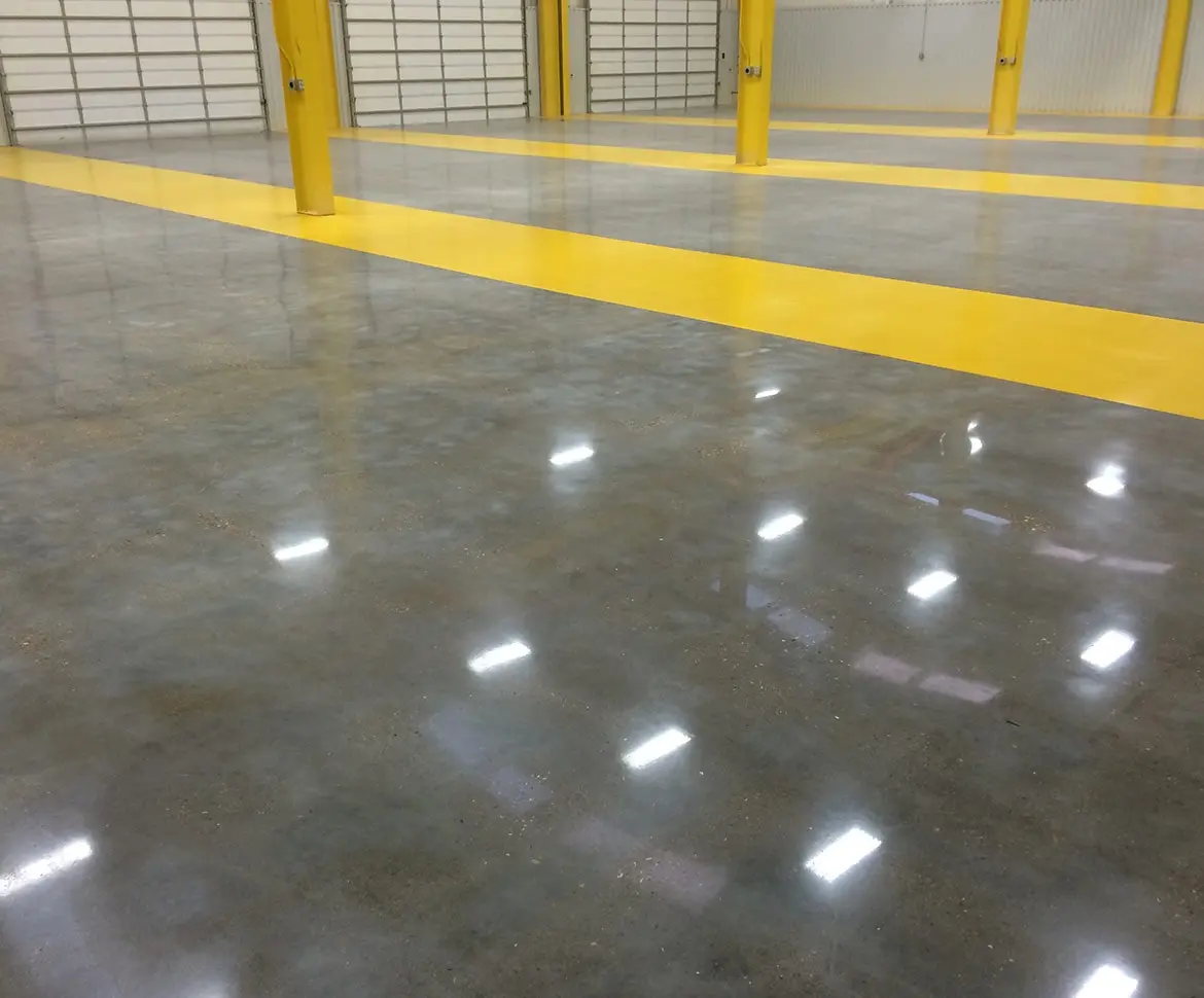 Light grey traffic coating on heavy vehicle maintenance bay floor with yellow parking lines and utility truck