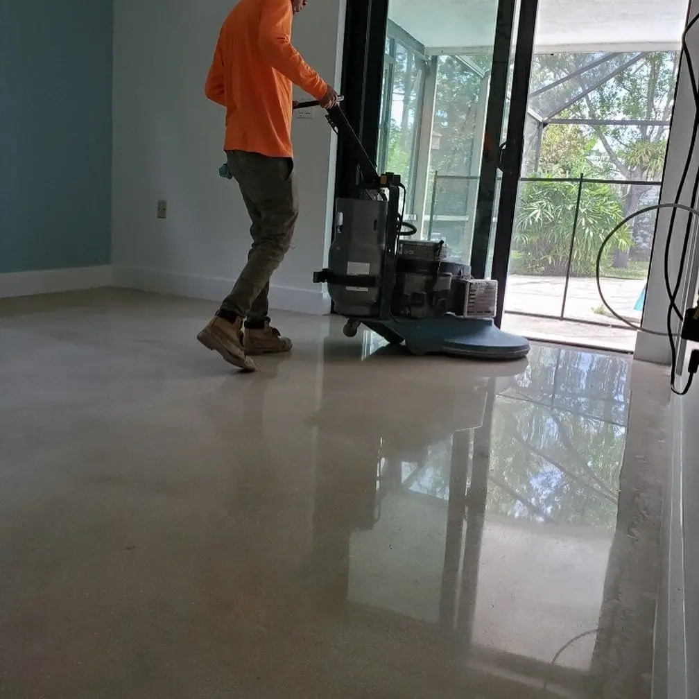 Worker polishing epoxy quartz flooring in a bright commercial space