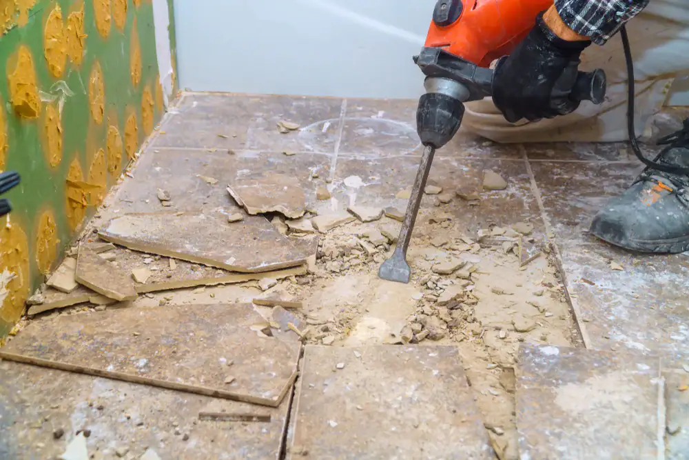 Residential tile removal with electric hammer drill breaking floor tiles