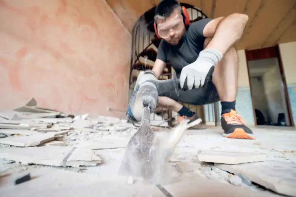 Worker using power tool to remove VCT flooring in commercial space